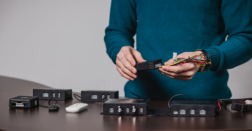 Person connecting actuator control system wiring modules on a table